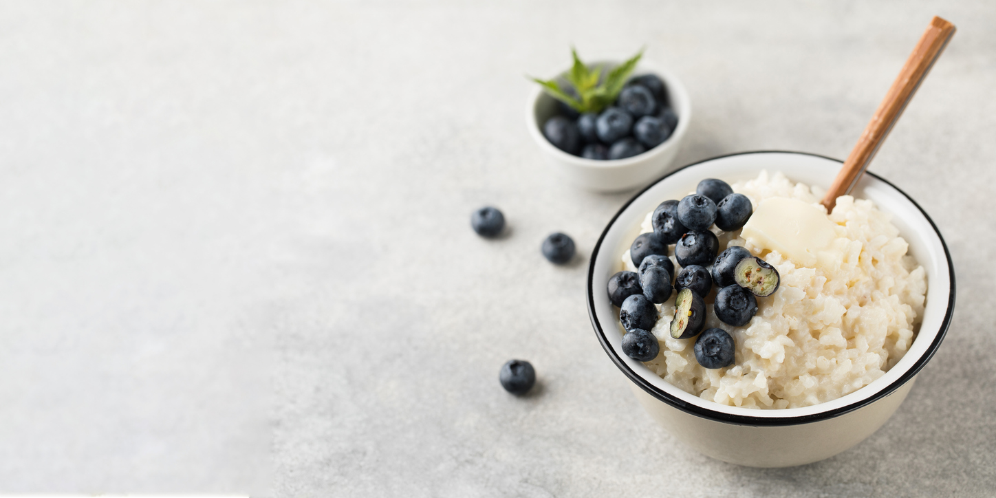 Rice milk porridge with blueberries in a bowl close-up. The concept of a healthy and tasty breakfast. Copy space